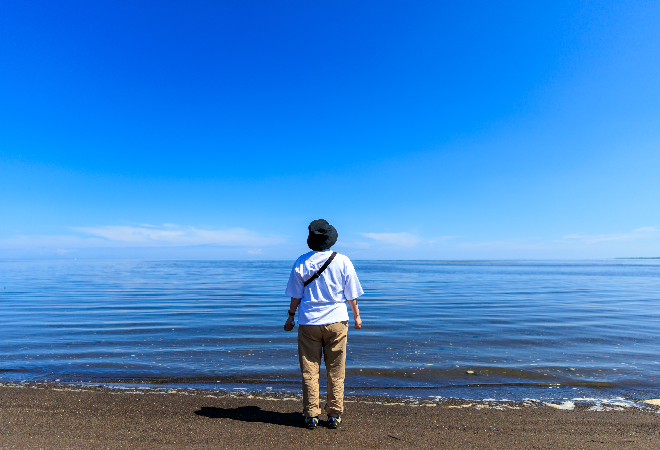 海辺に佇む女性の後ろ姿。