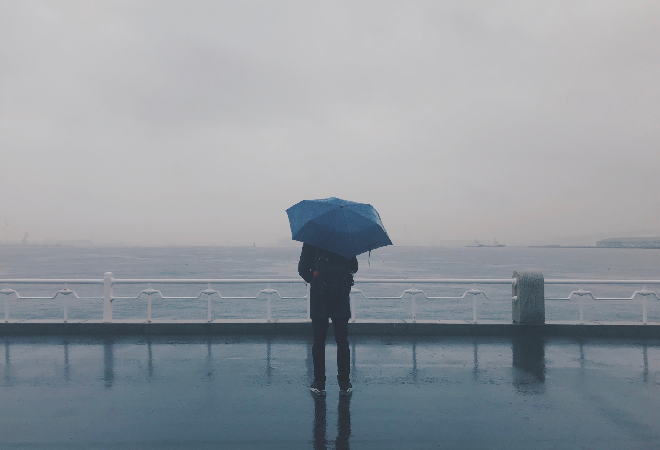 傘をさす男性の後ろ姿。