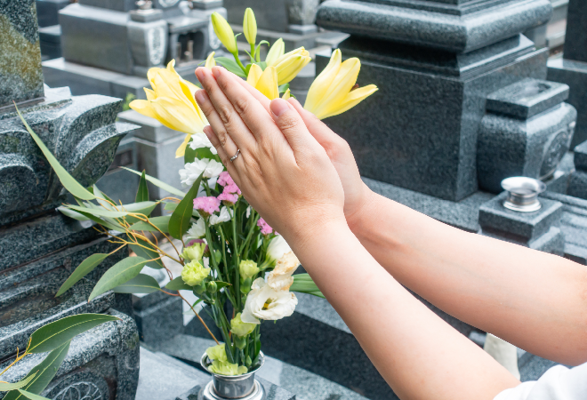 お墓の前で手を合わせている。
