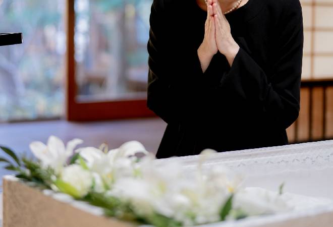 棺に手を合わせる女性。