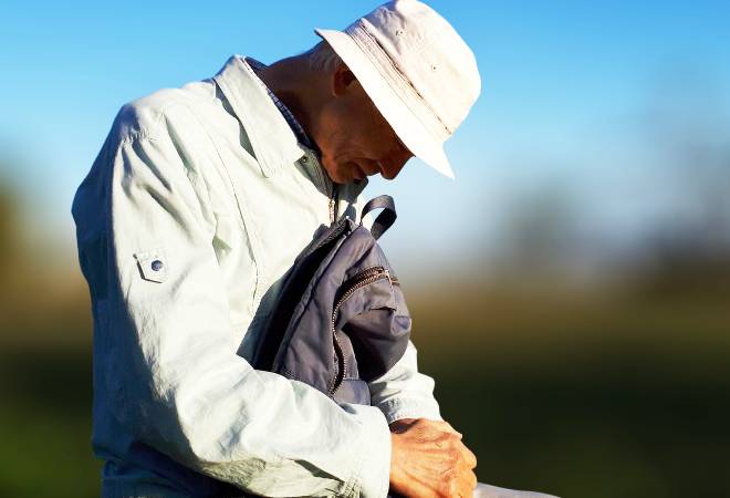 ベンチで項垂れる高齢男性の姿。